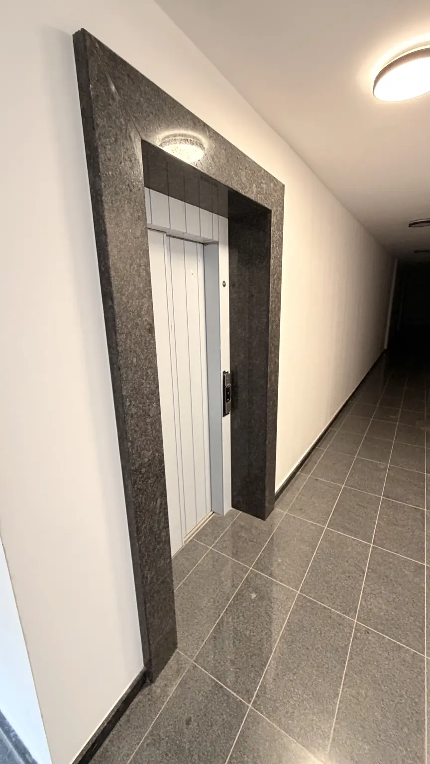 Етажно фоайе пред асансьора с портал от тъмен гранит / Floor lobby in front of the elevator with dark granite portal